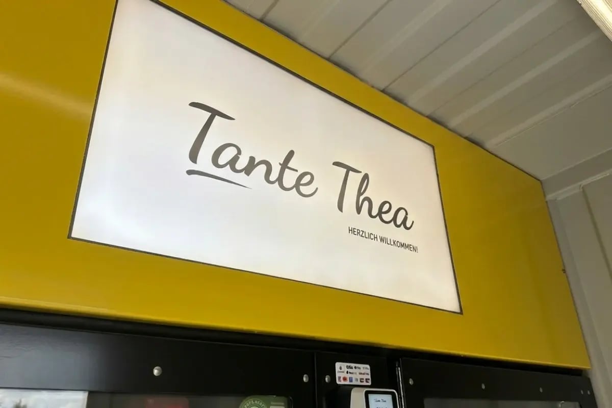 Digitaler Bildschirm über den Automaten eines Tante-Thea-Standorts.