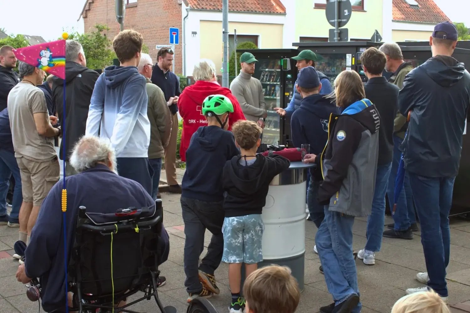 Menschen aus Hetlingen kommen bei der Vorstellung des Tante Thea Standorts vor den Verkaufsautomaten zusammen.